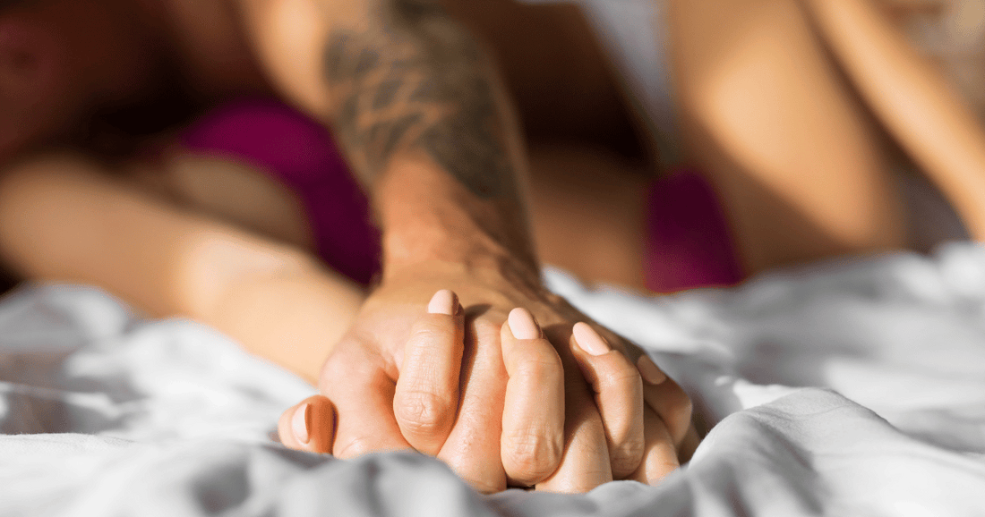 man holding hands with woman in bed with pink nails