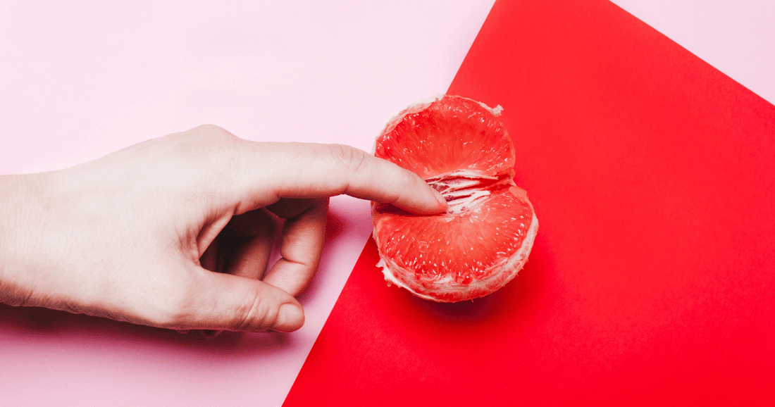 woman with pointer finger on grapefruit with pink and red background