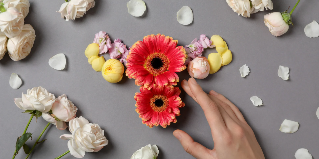 Overhead shot of a floral arrangement on a gray background with a hand gently touching it.