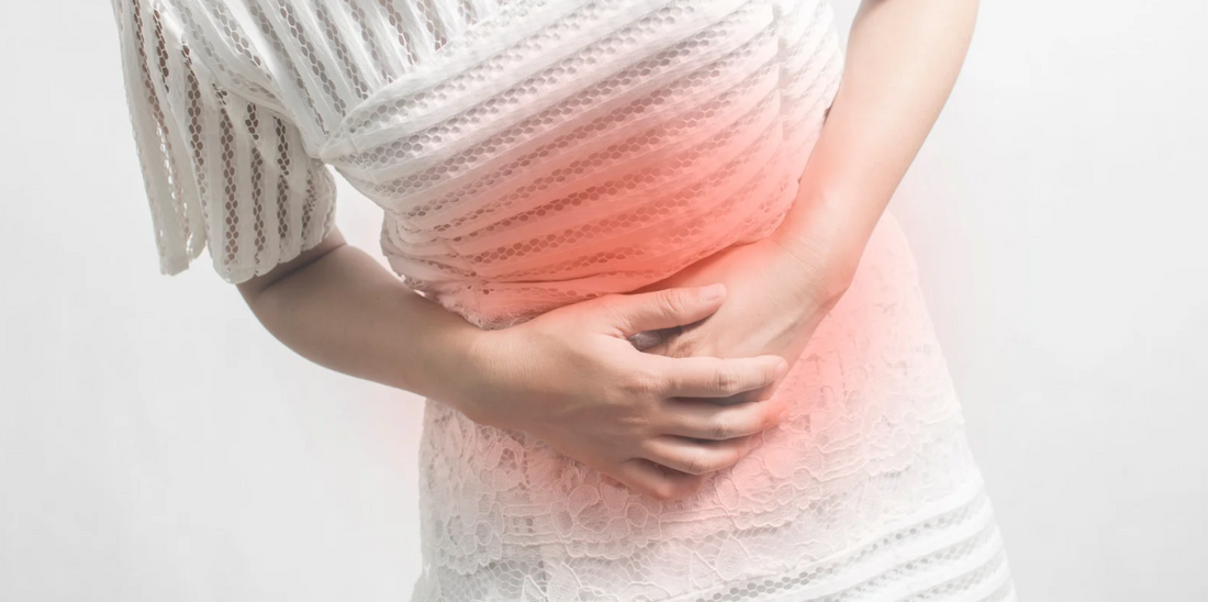 A person in a white dress is holding their stomach with both hands