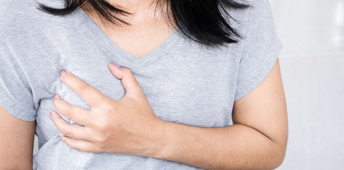 A person holding their chest, wearing a gray shirt.