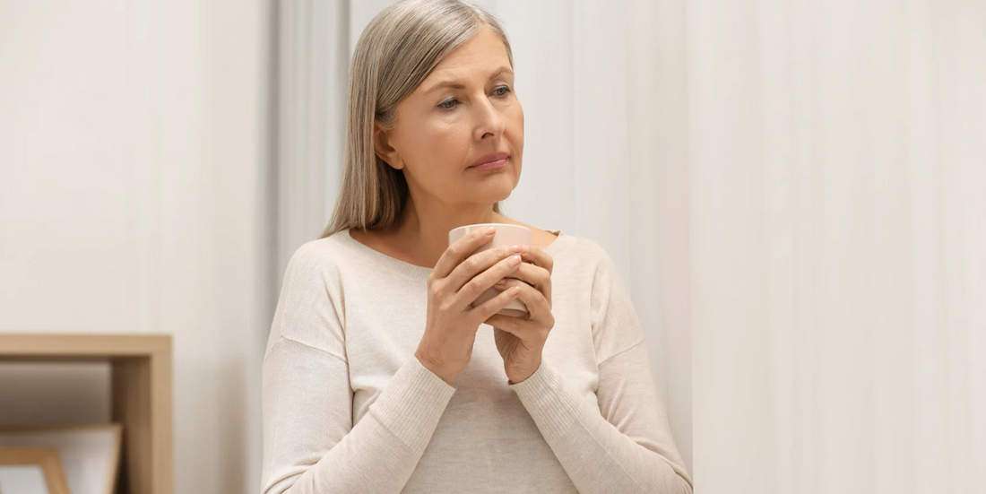 Pensive woman holds steaming mug.