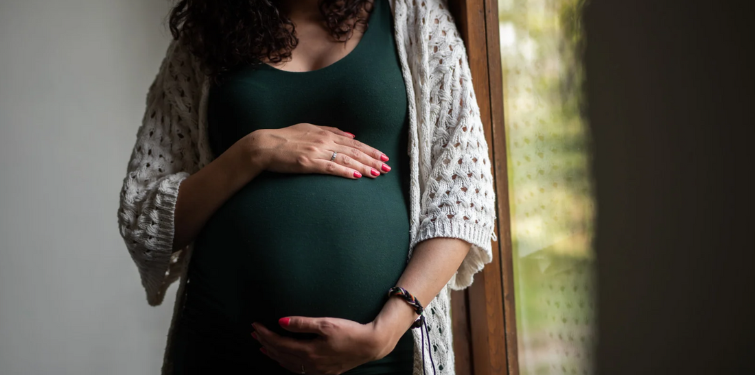 Pregnant woman embraces baby bump.