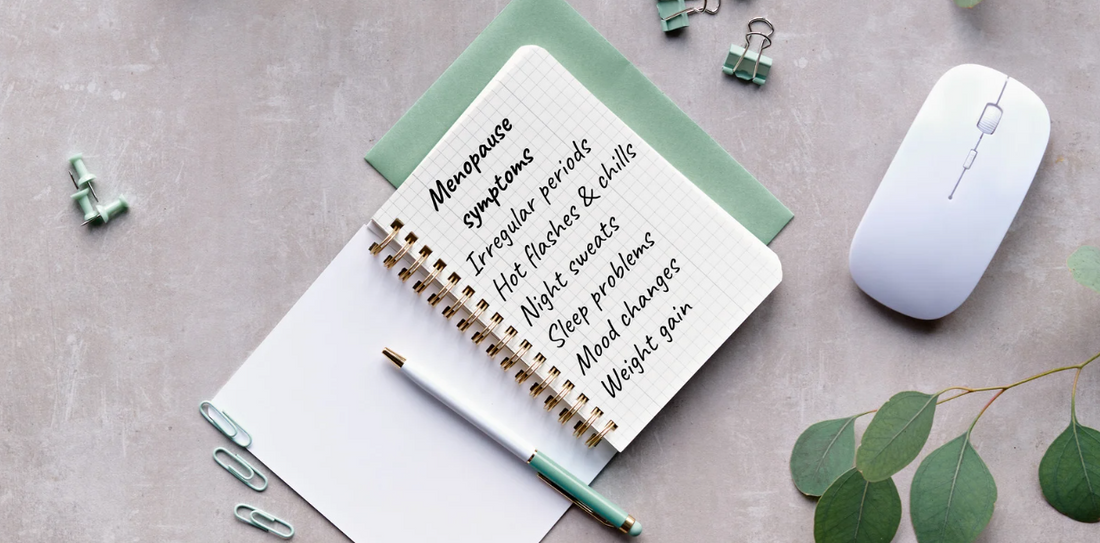 An overhead shot showing office supplies and a notebook on which the symptoms of menopause are listed.