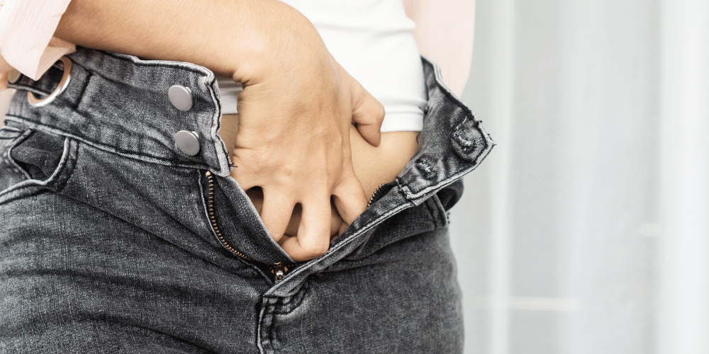 The image shows a person holding a pair of jeans.