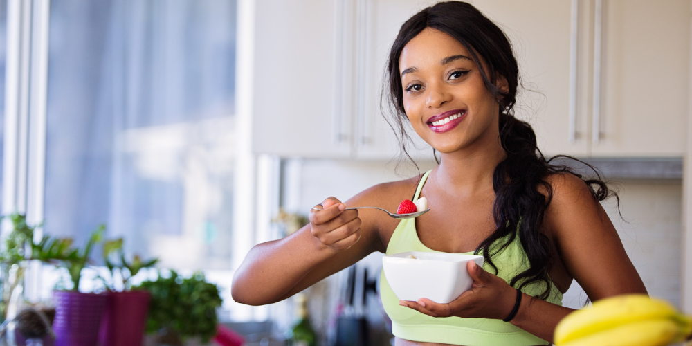 The image shows a woman holding a bowl of salad with a smile.