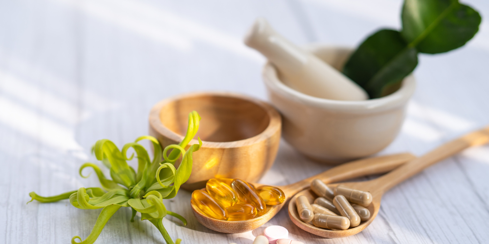 The image features a few bowls of pills alongside a plant. The setting appears to be in a kitchen or dining area.