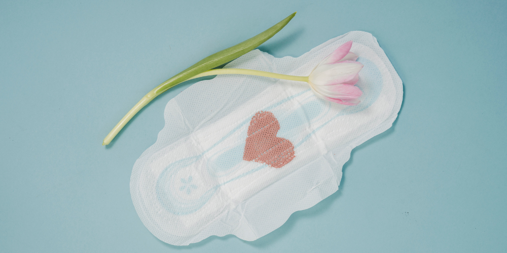 An image of a napkin with a heart on it and a flower beside it.