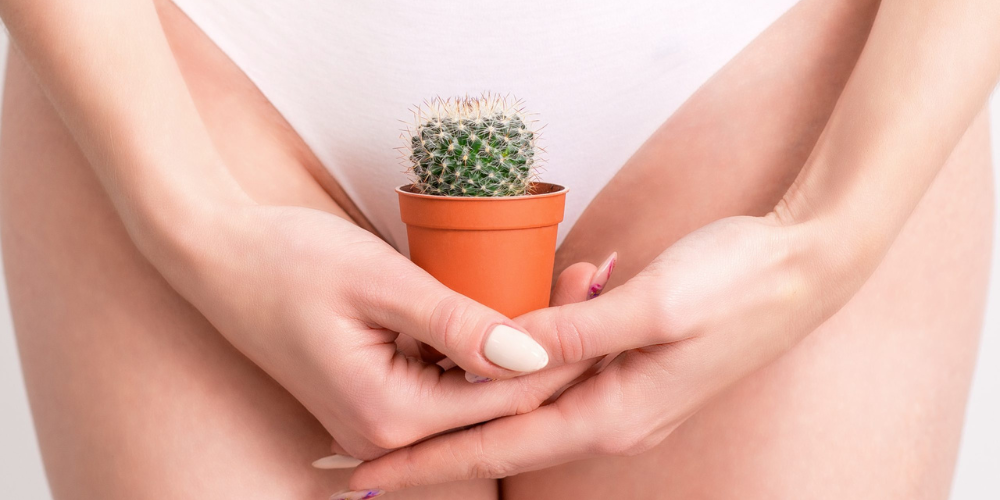 The image features a woman holding a plant in a flowerpot. Her hand, fingers, and nails are visible in the photo near her pelvis.