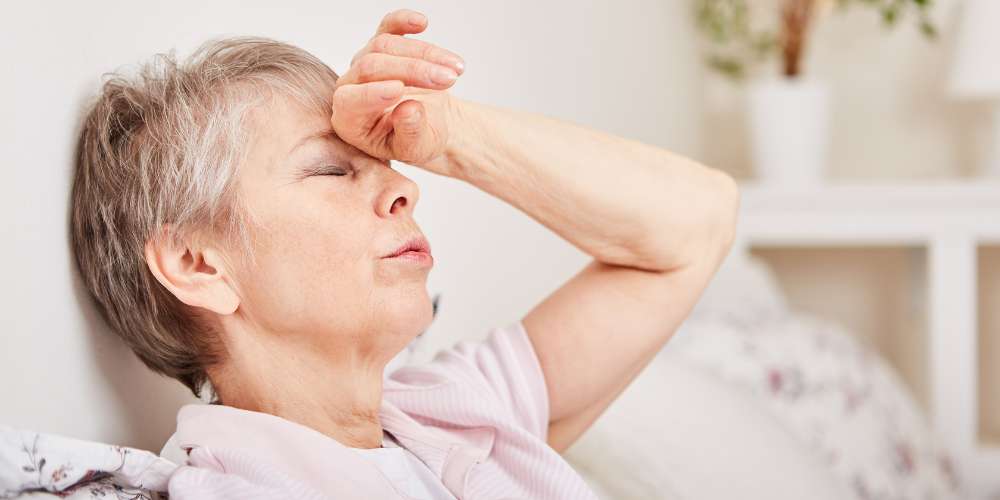 The image shows an old woman with her hand on her forehead.