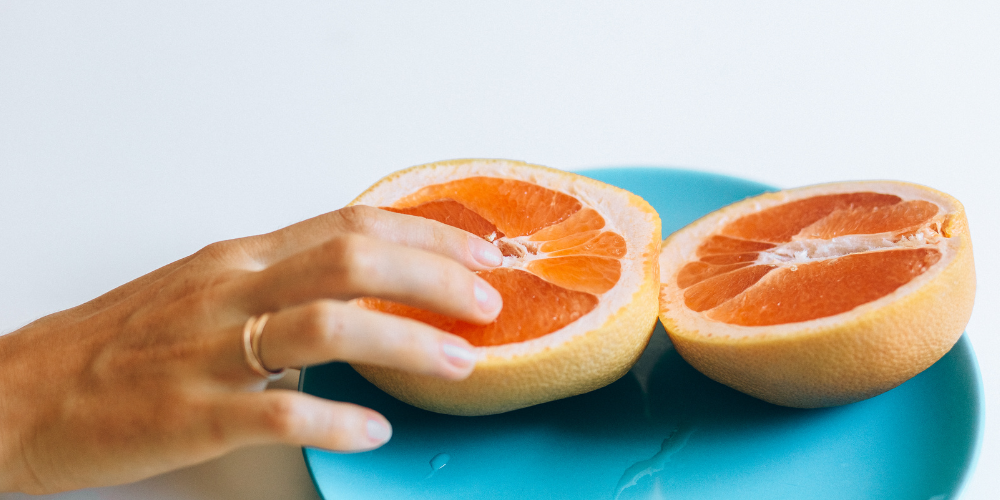 The image shows a person holding an orange indoors. The tags associated with the image include fruit, citrus, orange, peel, and person.