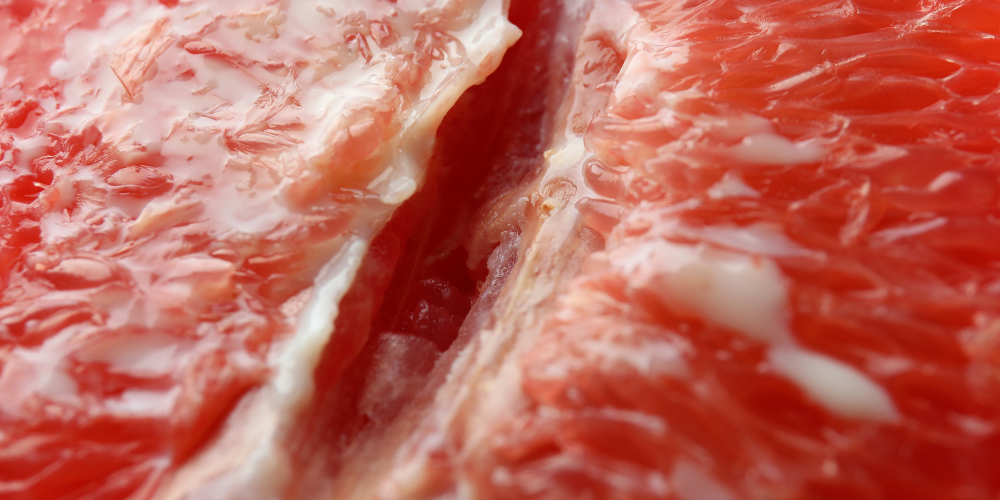 The image is a close-up of a red substance that could be animal fat, grapefruit, meat, or fruit flesh, possibly related to citrus.