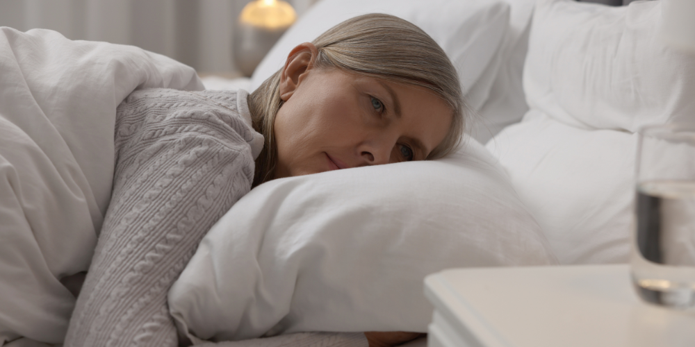 The image shows a person lying in a bed. The person appears to be resting comfortably with a blanket. The photo features a woman or a newborn girl.