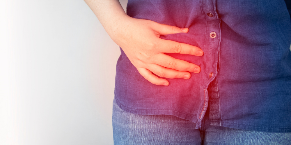 The image shows a woman's pelvis and her hand holding her lower abdomen.