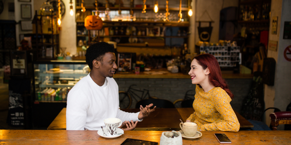 The image depicts a man and a woman sitting at a table with tea cups in a restaurant.