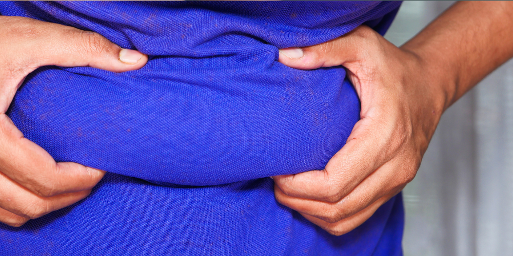 The image is a close-up shot of a person holding a blue shirt. The hand of the person is visible in the picture, showcasing the blue clothing item.