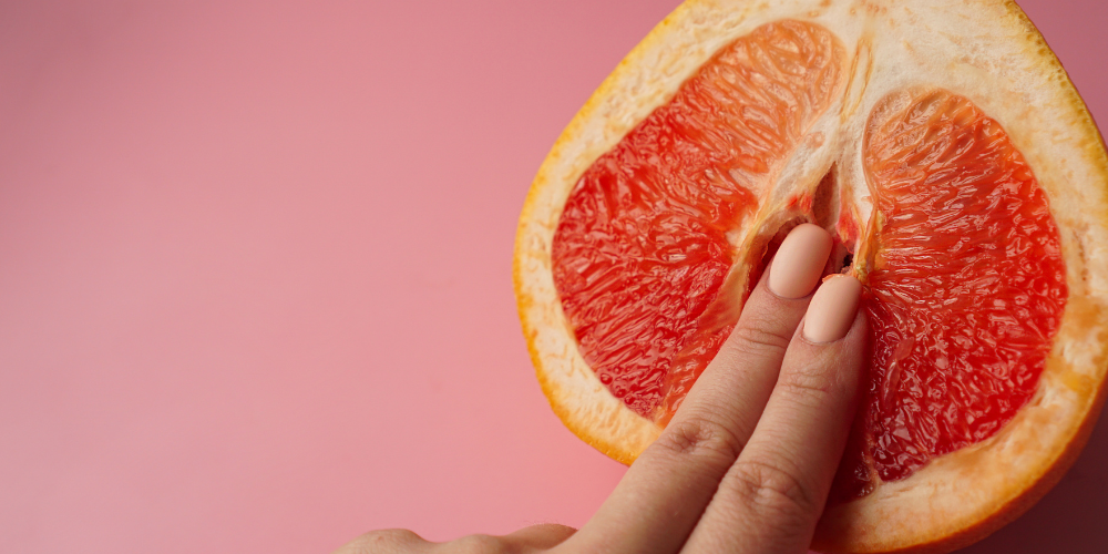 The image is of a hand holding a slice of orange. It depicts a citrus fruit being held by a person.