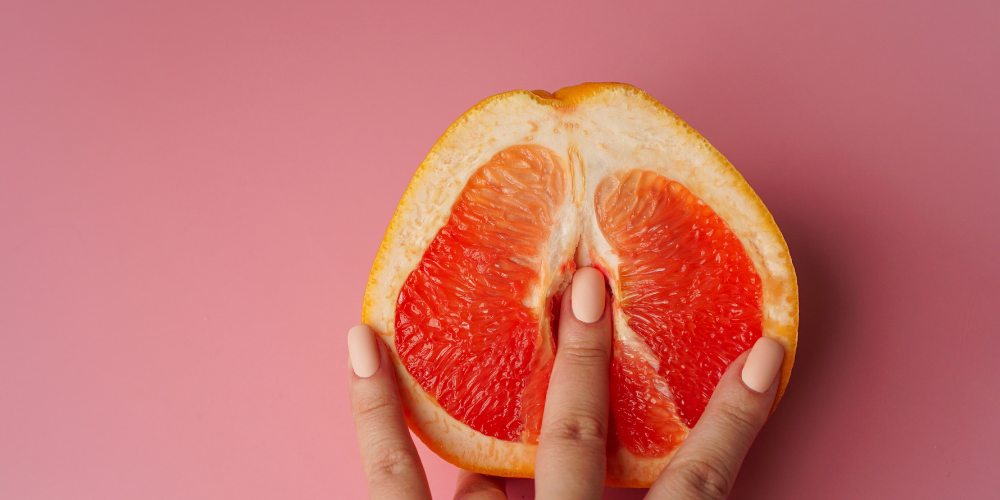 The image is of a hand holding a slice of orange.