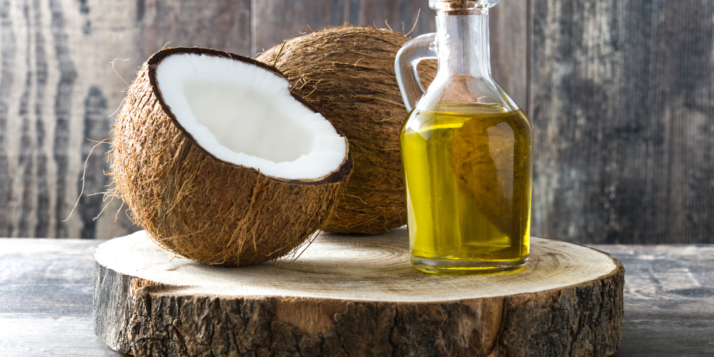 The image shows a jar of coconut food and a glass bottle on a wooden surface outdoors.