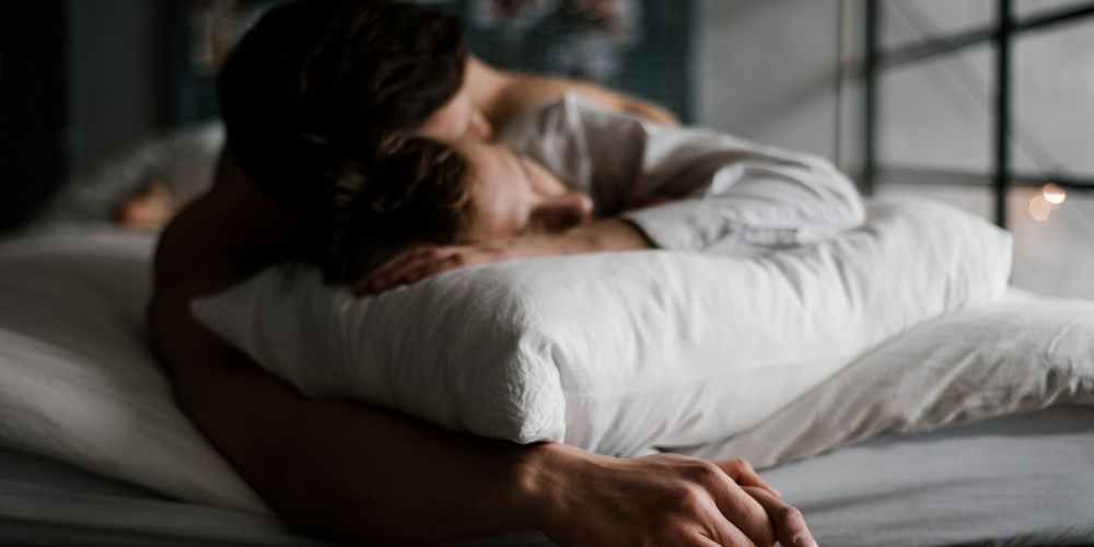 The image shows a man and a woman sleeping together. They are lying on a bed, covered with bedclothes.