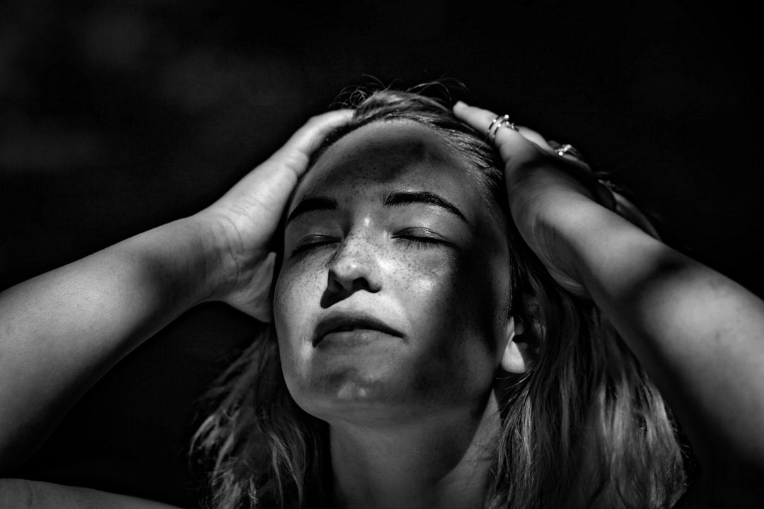 grayscale photography of woman holding her head