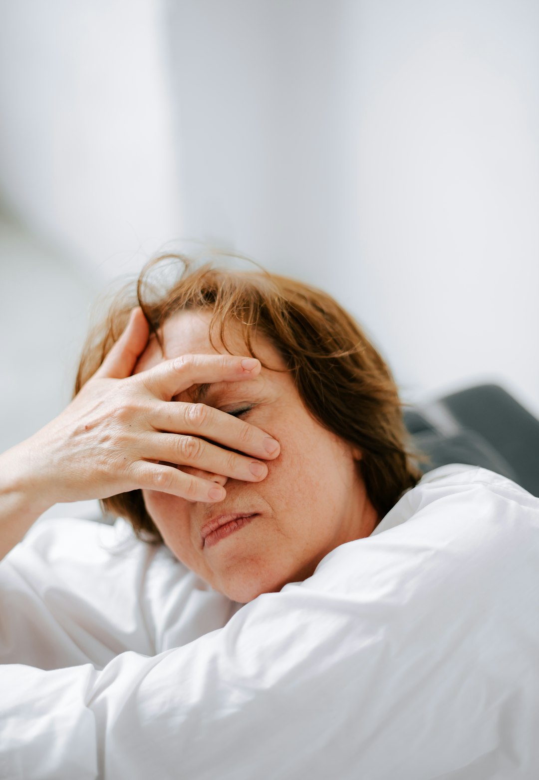 a woman laying in bed with her hands on her head