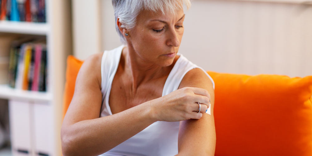 a woman putting a white patch on her arm