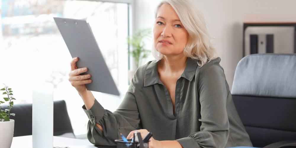 a woman in a grey top and holding a tablet