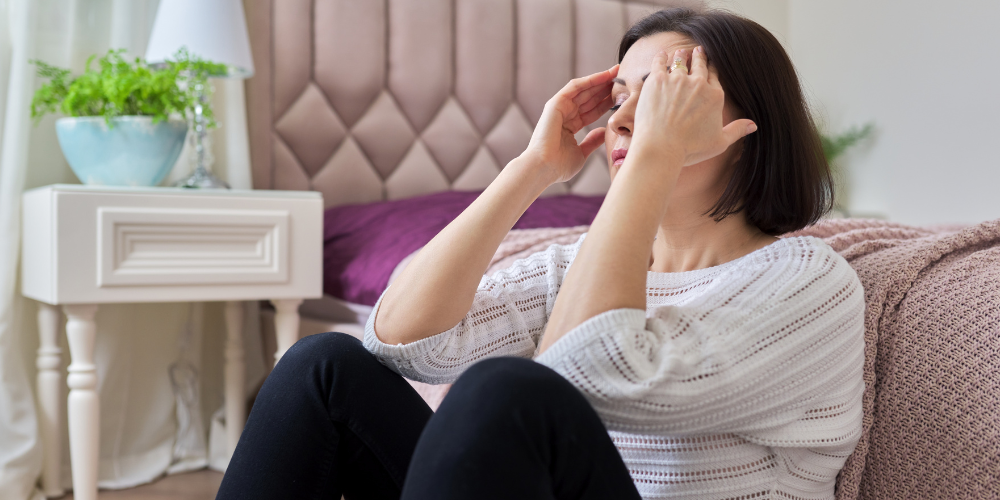 The image shows a woman sitting in her bedroom.