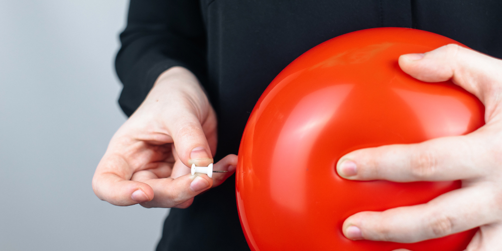 a person holding a pin and a balloon