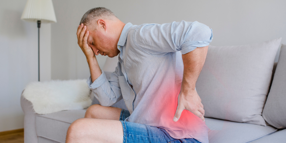 The image shows a man holding back hip in pain.