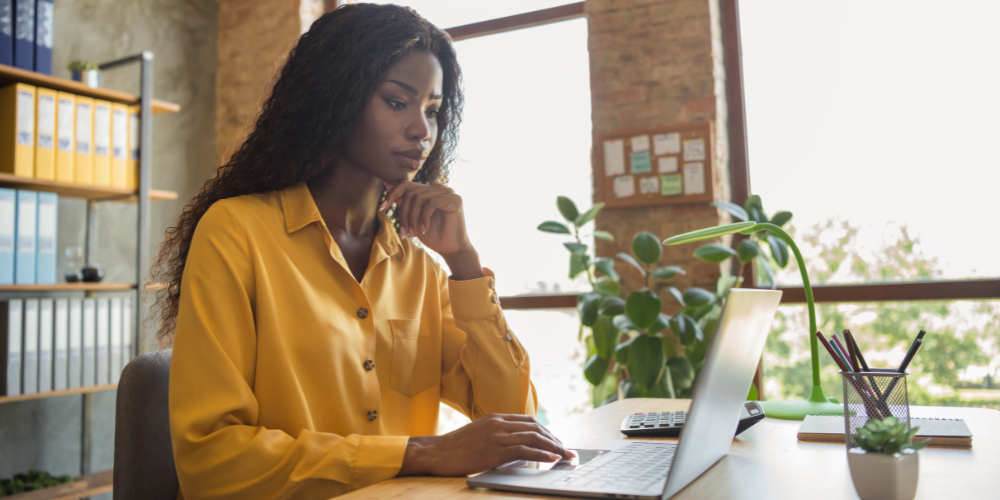 a woman in yellow top looking at her laptop