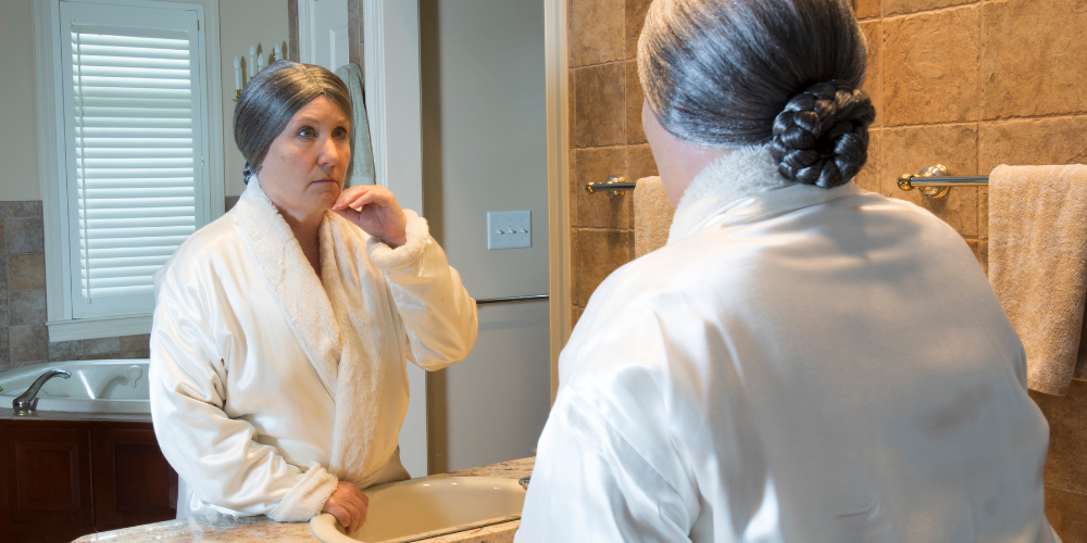 an old woman inside a bathroom wearing a robe