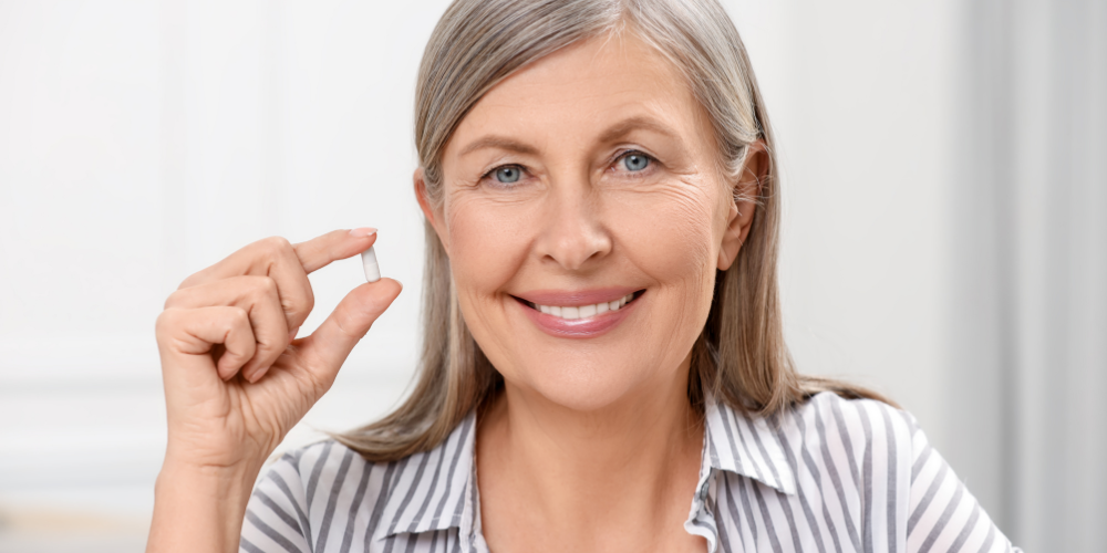 The image shows a woman holding a pill.