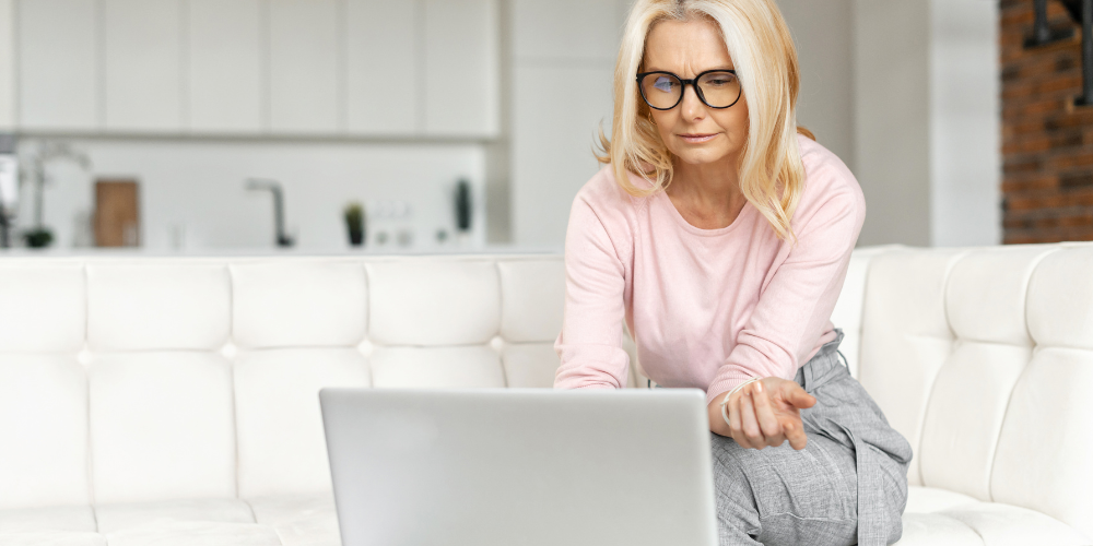 a woman sitting indoors while looking at her laptop