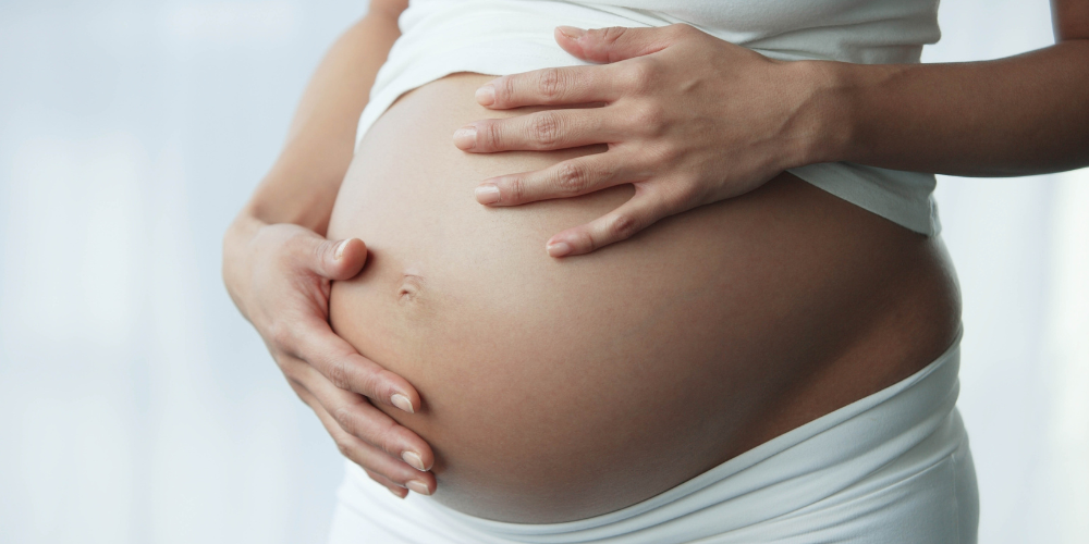 The image shows a woman holding her belly.