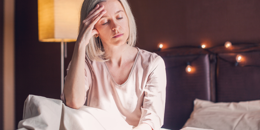 A woman is sitting on a bed indoors.