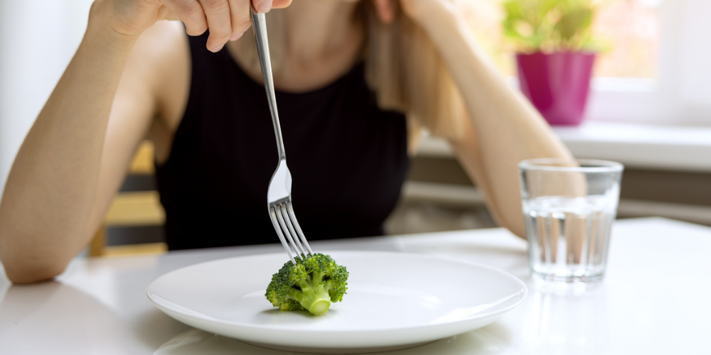 a woman eating a broccoli 